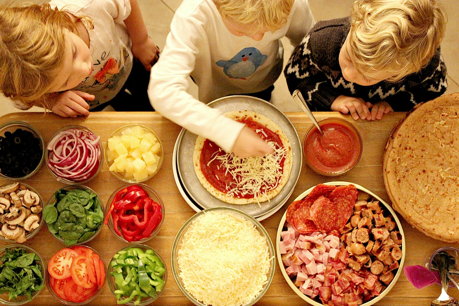 Kids and adults making pizzas together at home